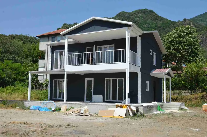 Koyu antrasit cepheli, beyaz balkon korkuluklu çift katlı prefabrik yapının ön görünümü